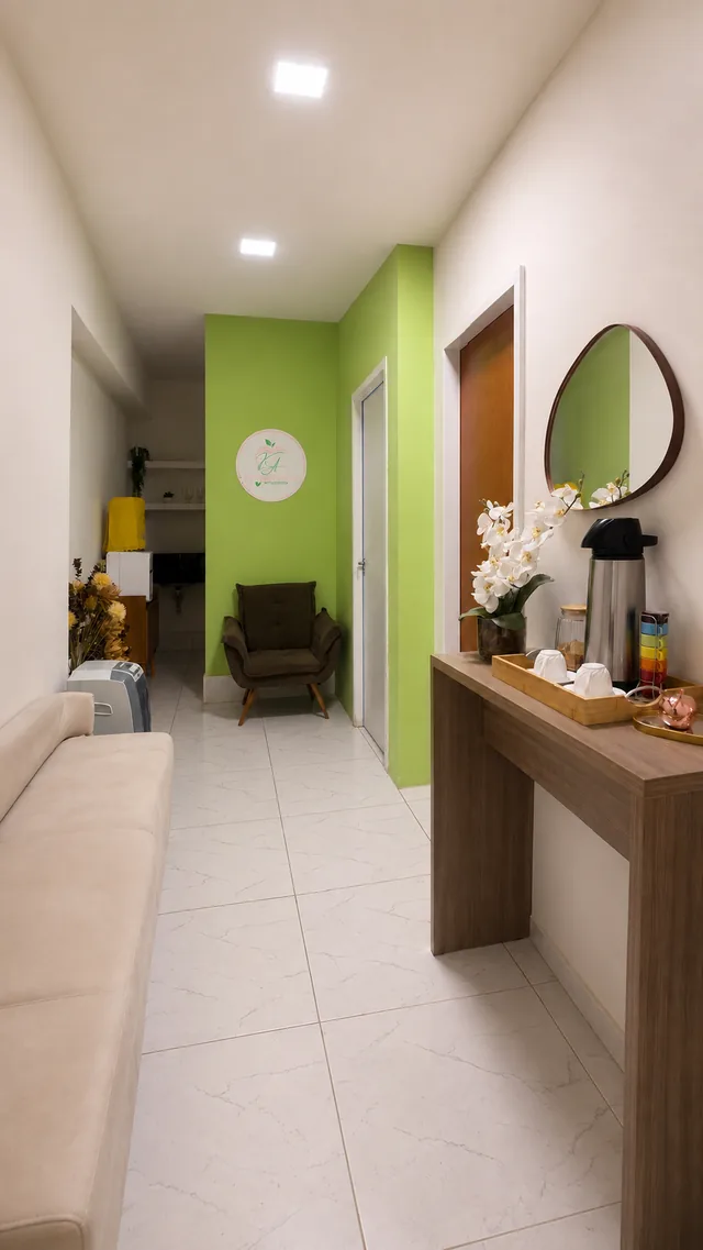 Recepção do consultório, com sofá de espera, aparador de apoio e parede verde ao fundo