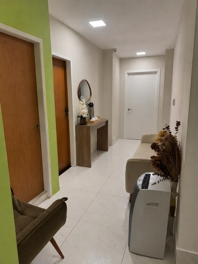 Vista de dentro da recepção, com as portas das salas de atendimento, poltrona e aparador